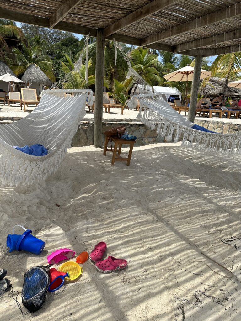 hammocks on a beach with sand and umbrellas and chairs and umbrellas