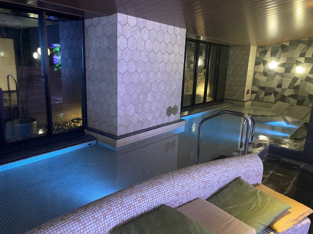 a indoor pool with a bench and a tile wall