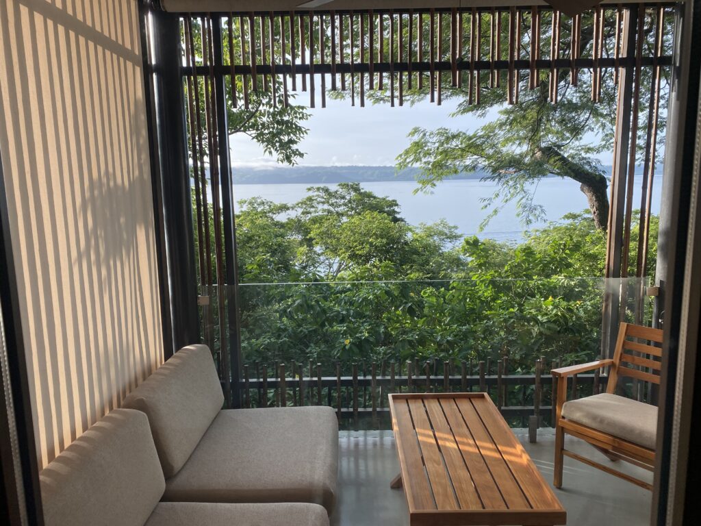 a couch and table outside with trees and water in the background
