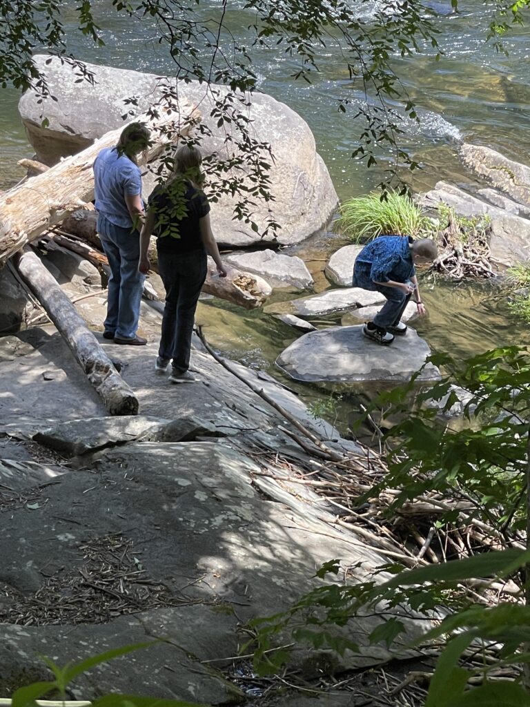 a group of people standing on rocks by a river