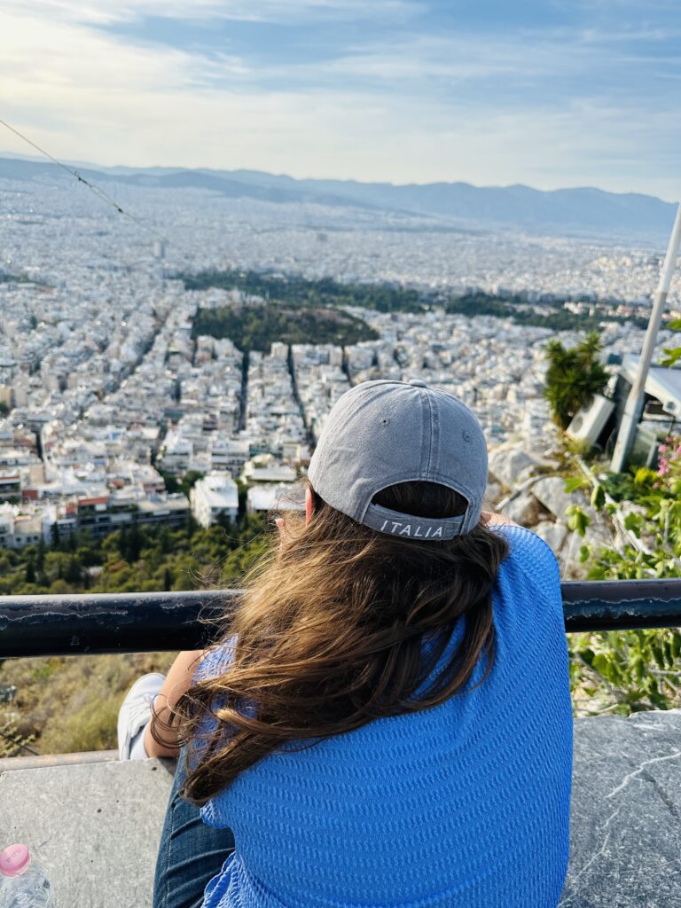a person sitting on a ledge overlooking a city