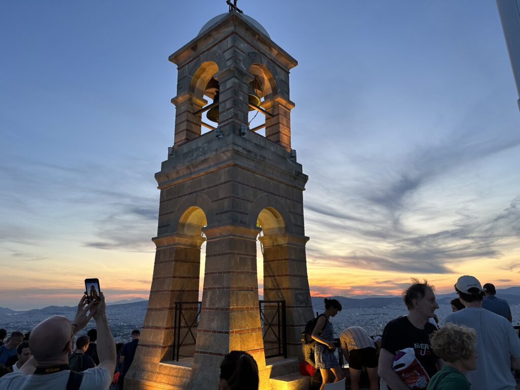 a tower with a bell and people standing around