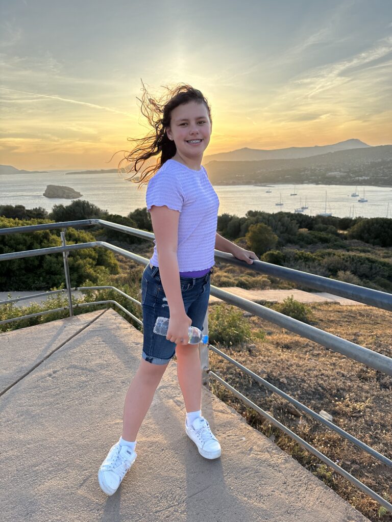 a girl standing on a railing with water in the background