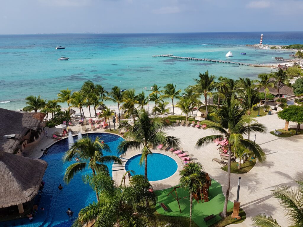 a pool and palm trees by a body of water
