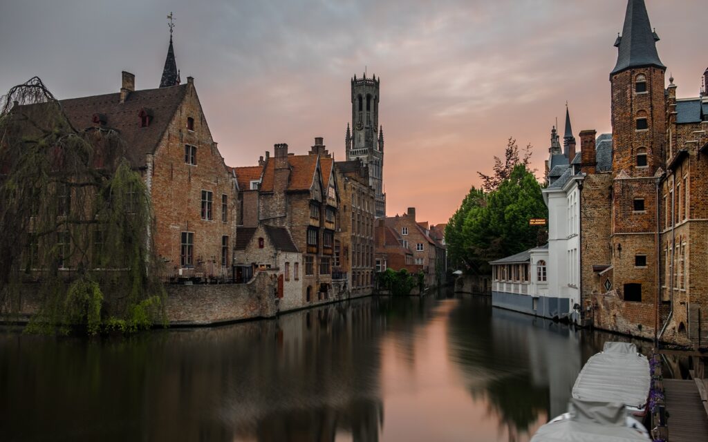 a water way with buildings and trees with Bruges in the background