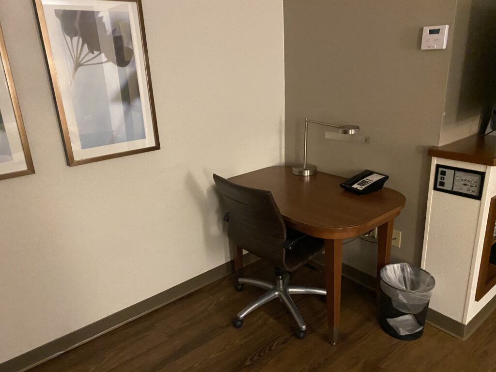 a desk with a chair and a lamp in a room