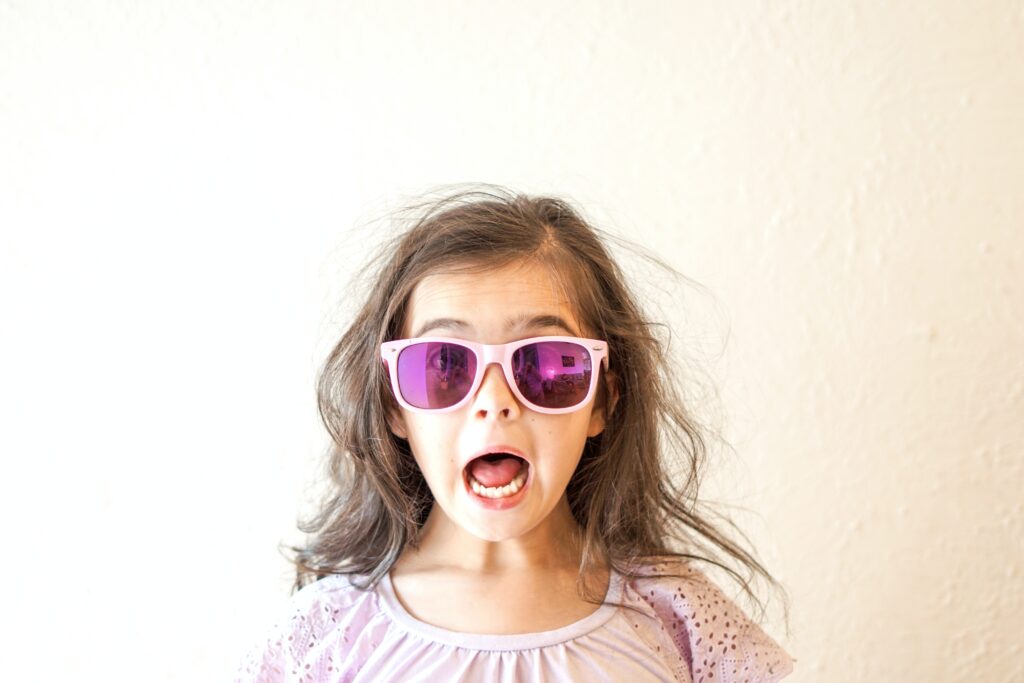 a girl wearing pink sunglasses and making a face