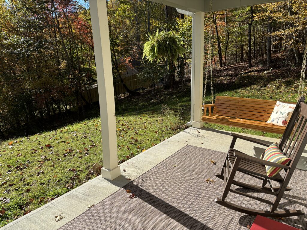 a porch with a swing and a lawn in the background