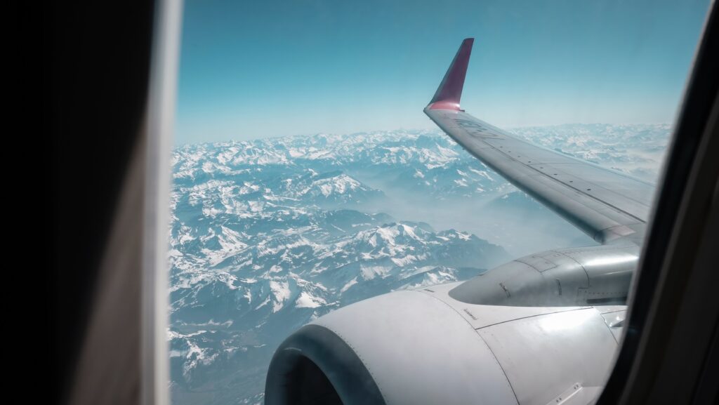 an airplane wing and snow covered mountains