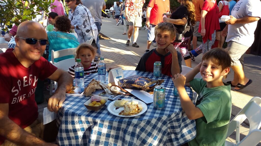 a group of kids sitting at a table with food and drinks