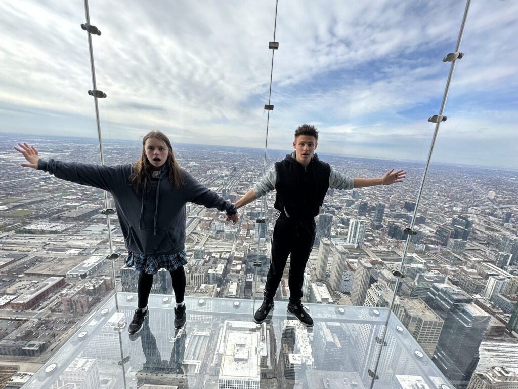 a boy and girl standing on a glass floor with hands out