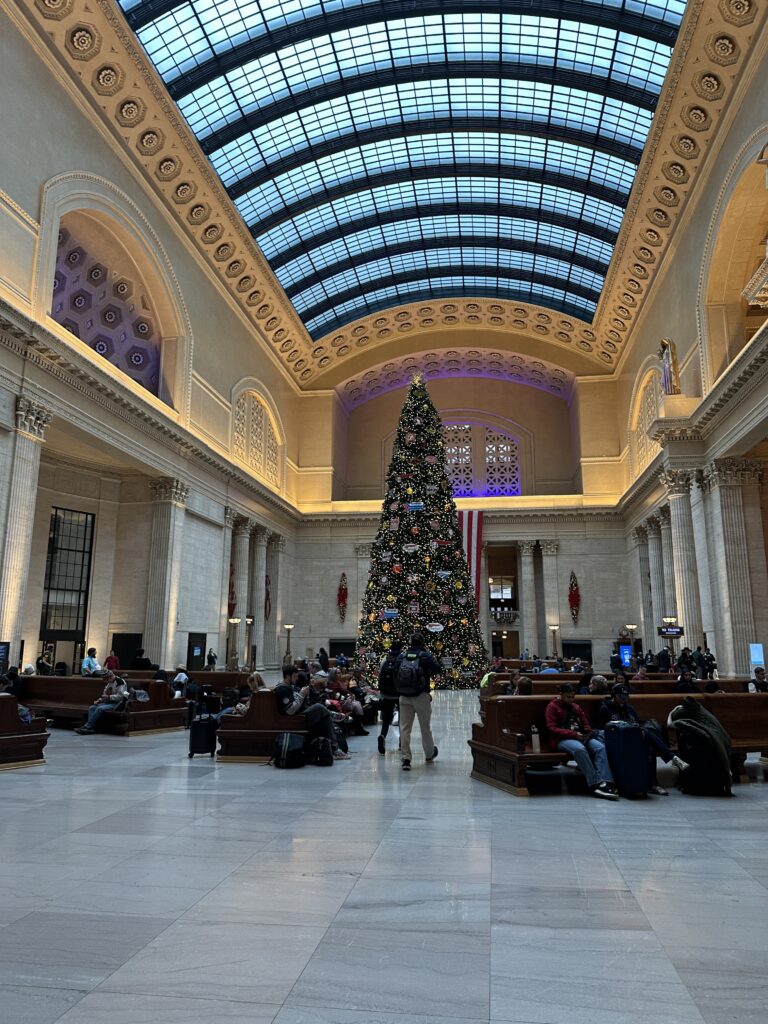 a large building with a christmas tree and people sitting on benches