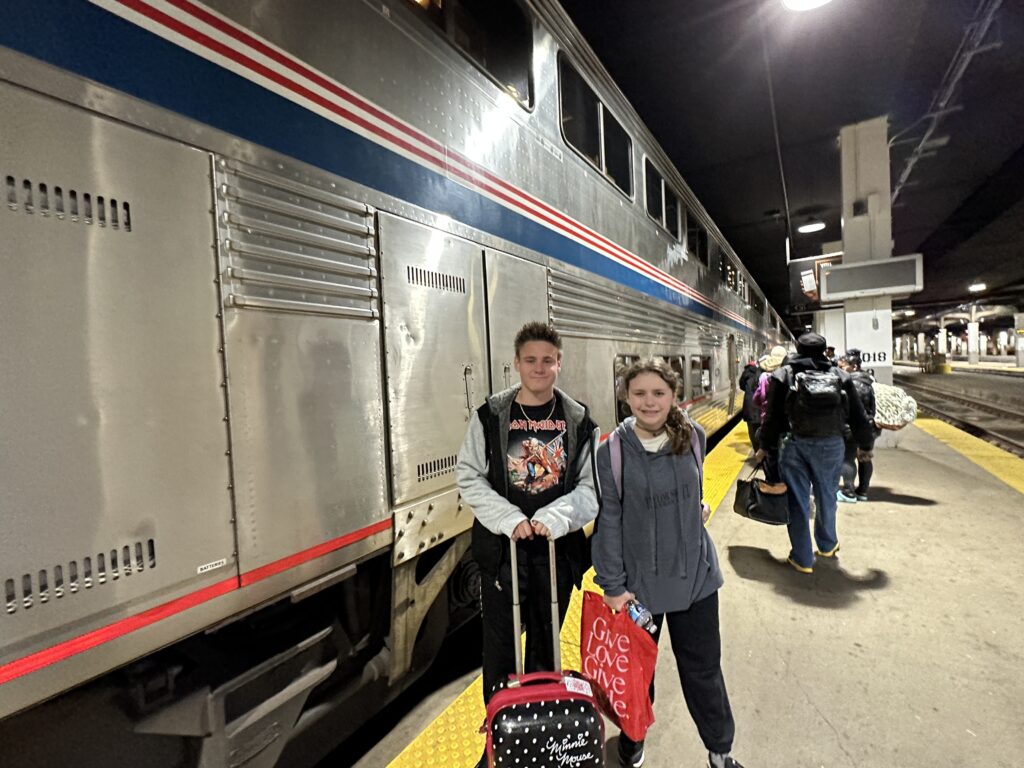 a boy and girl standing in front of a train