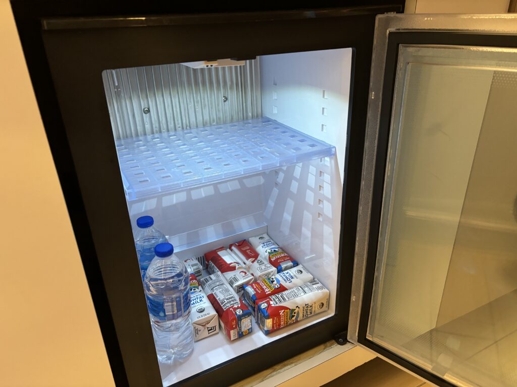 a refrigerator with a glass door and a shelf full of milk and water