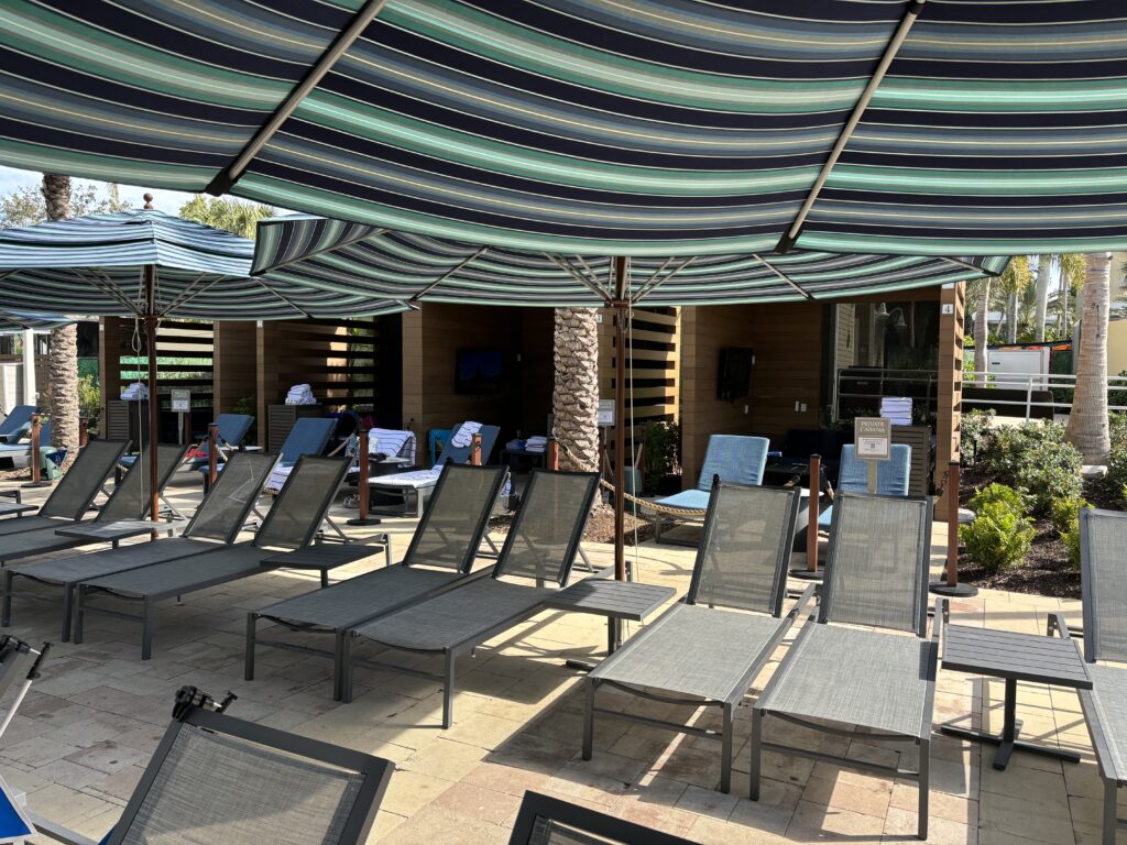a group of lounge chairs under a striped umbrella
