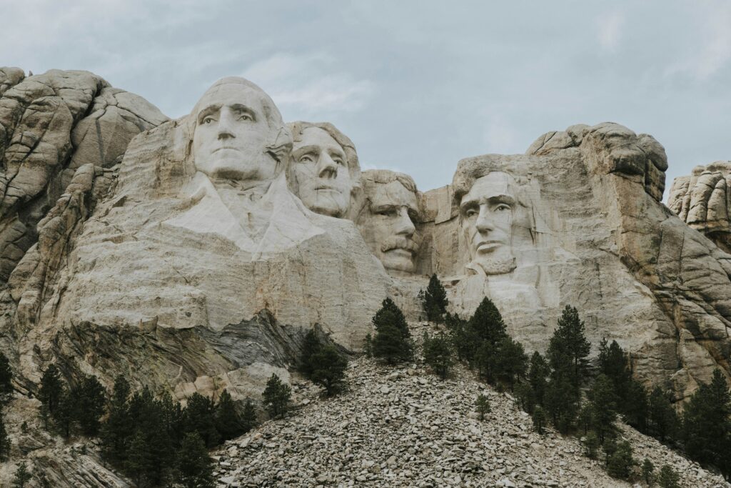 a large stone mountain with faces carved into it with Mount Rushmore National Memorial in the background