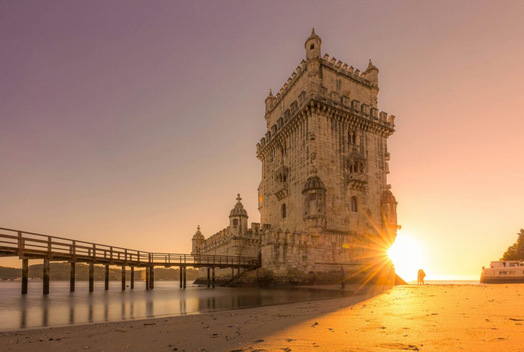 a stone castle with Belém Tower over water