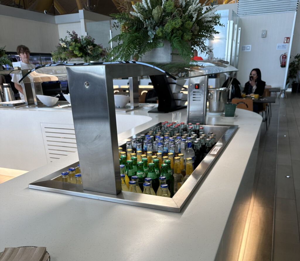 a counter with a cooler filled with soda bottles