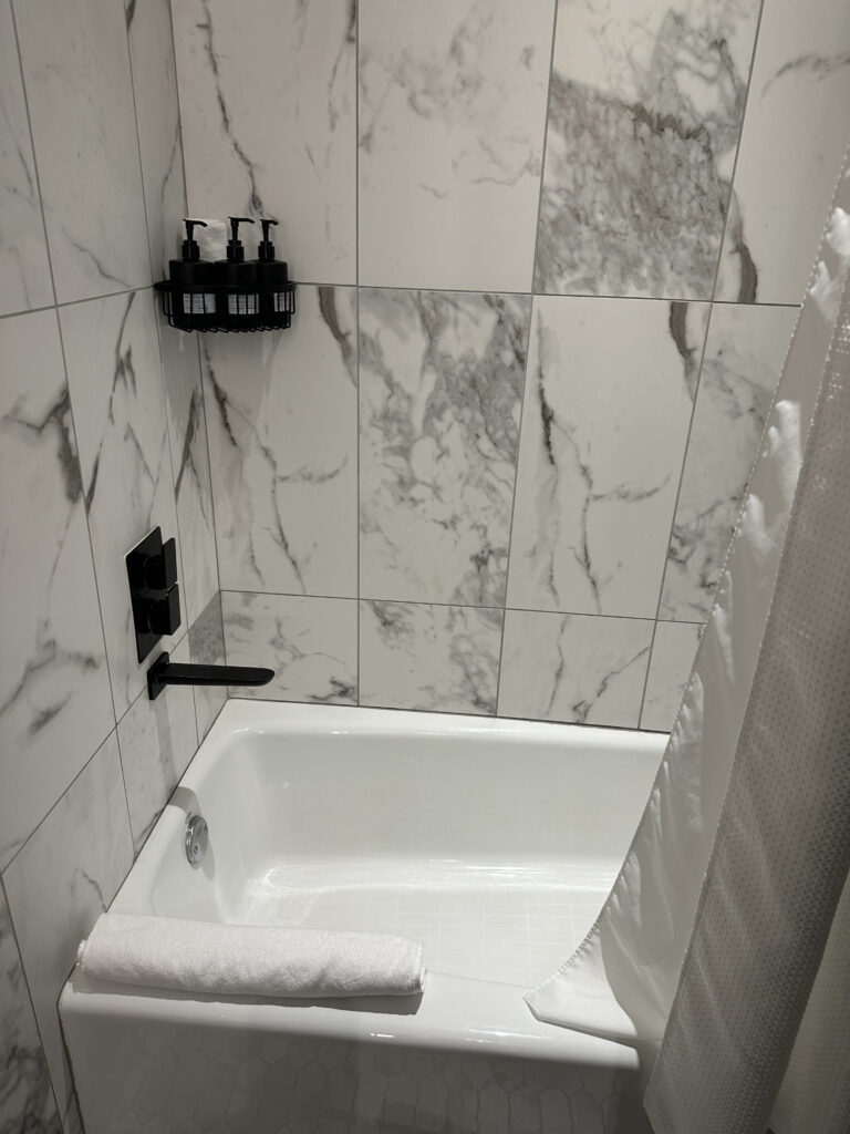 a white bathtub with a white curtain and black shower curtain