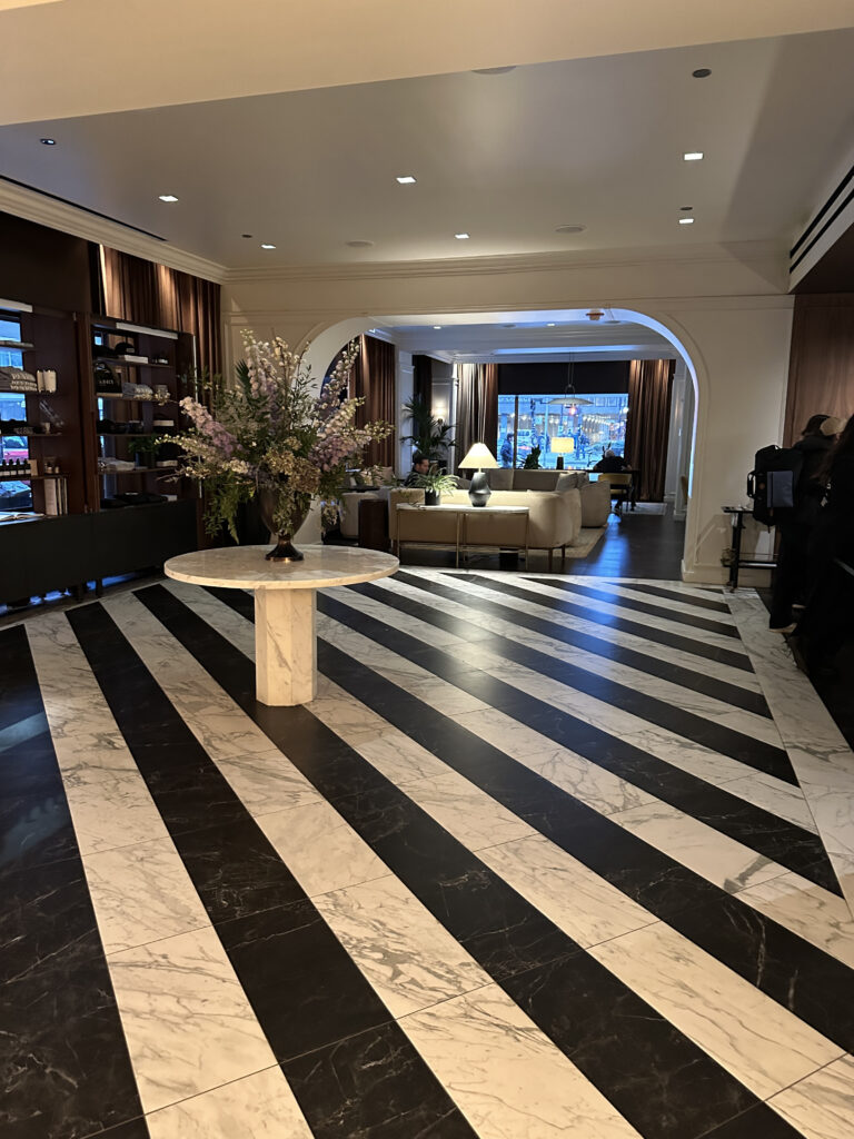 a black and white striped floor with a vase of flowers on a table