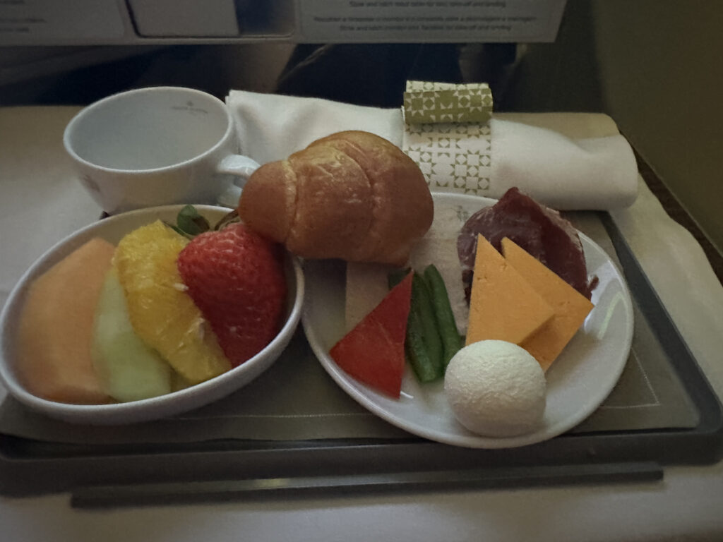 a plate of fruit and a croissant on a tray