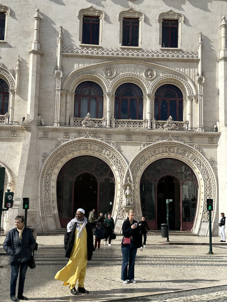 a man in a yellow dress walking in front of a large white building