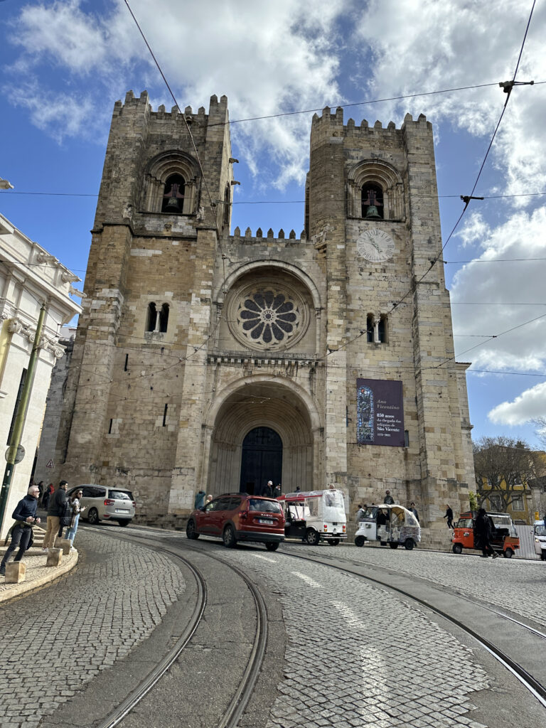 a stone building with a clock tower and people walking around with Nantes Cathedral in the background