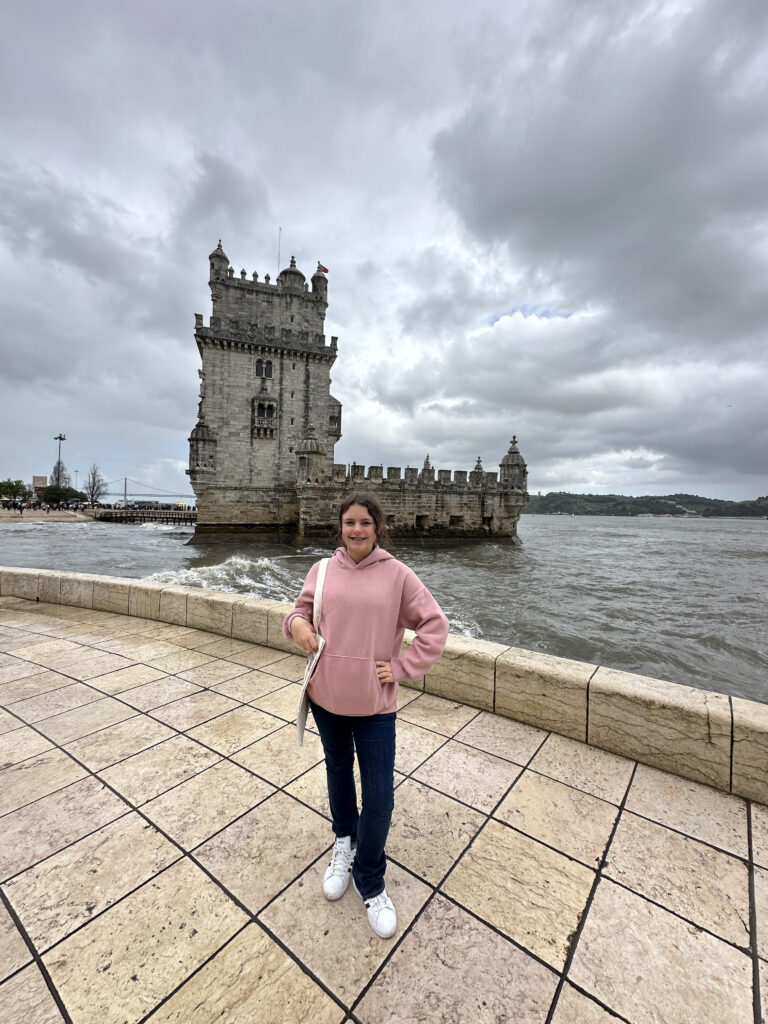 a woman standing on a stone walkway next to a large castle