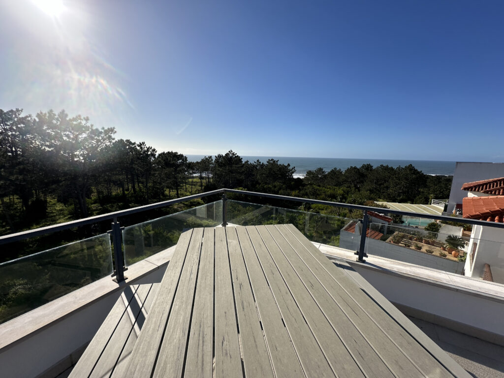 a deck with a glass railing overlooking a body of water