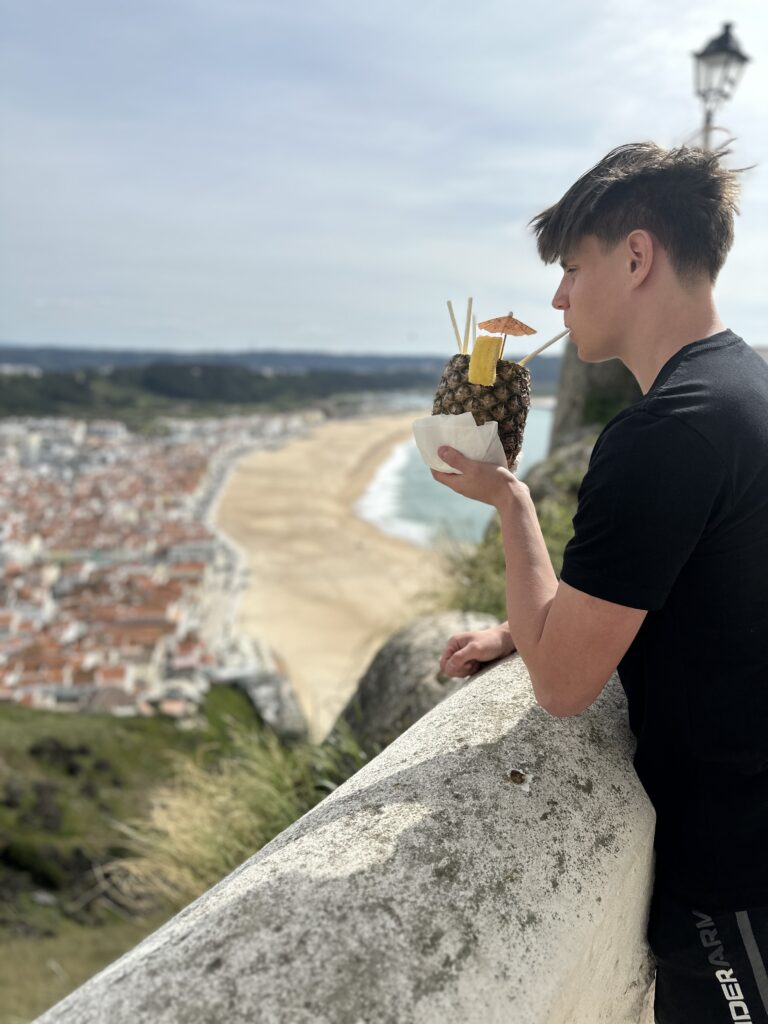 a man holding a pineapple and drinking from a cup