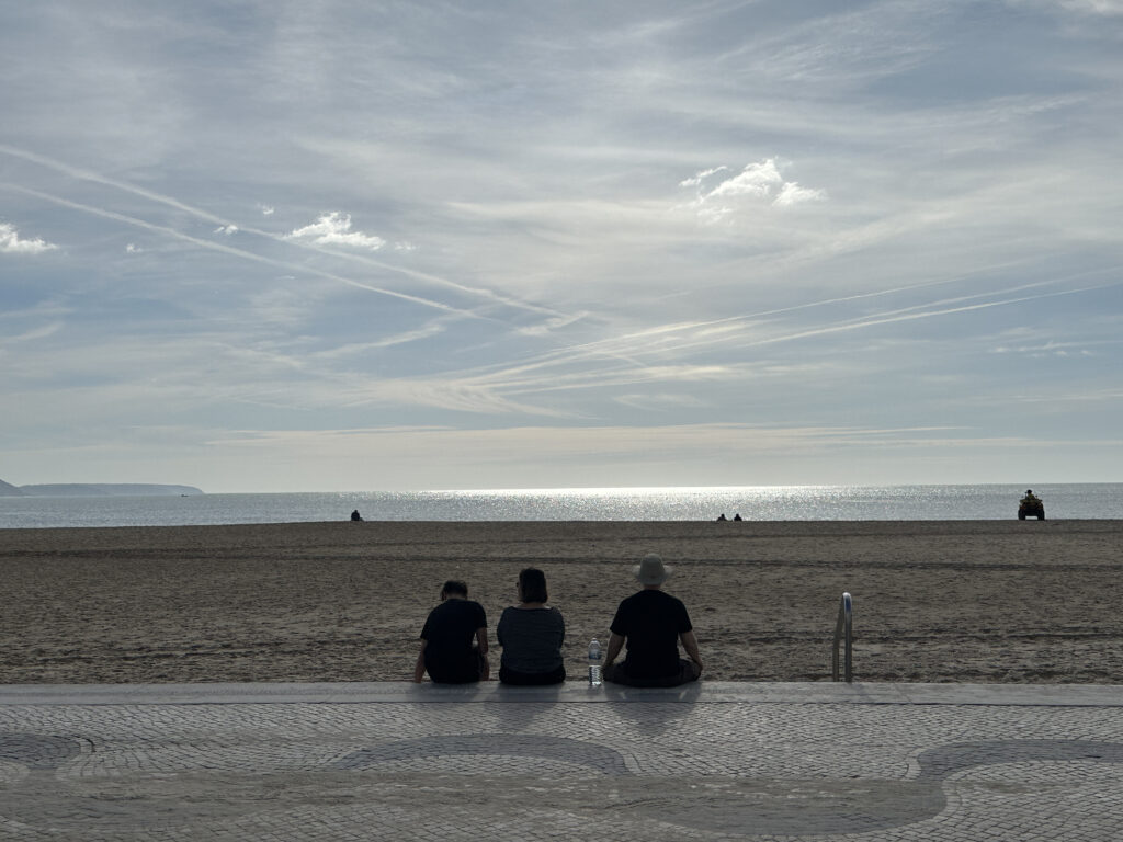 people sitting on a bench at the beach