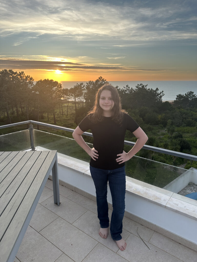 a girl standing on a balcony with a table and a table and a sunset