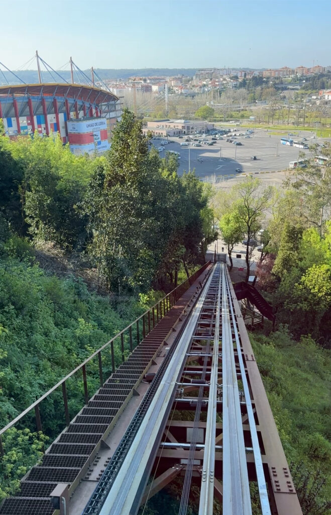 a track going down a hill with trees and a stadium in the background