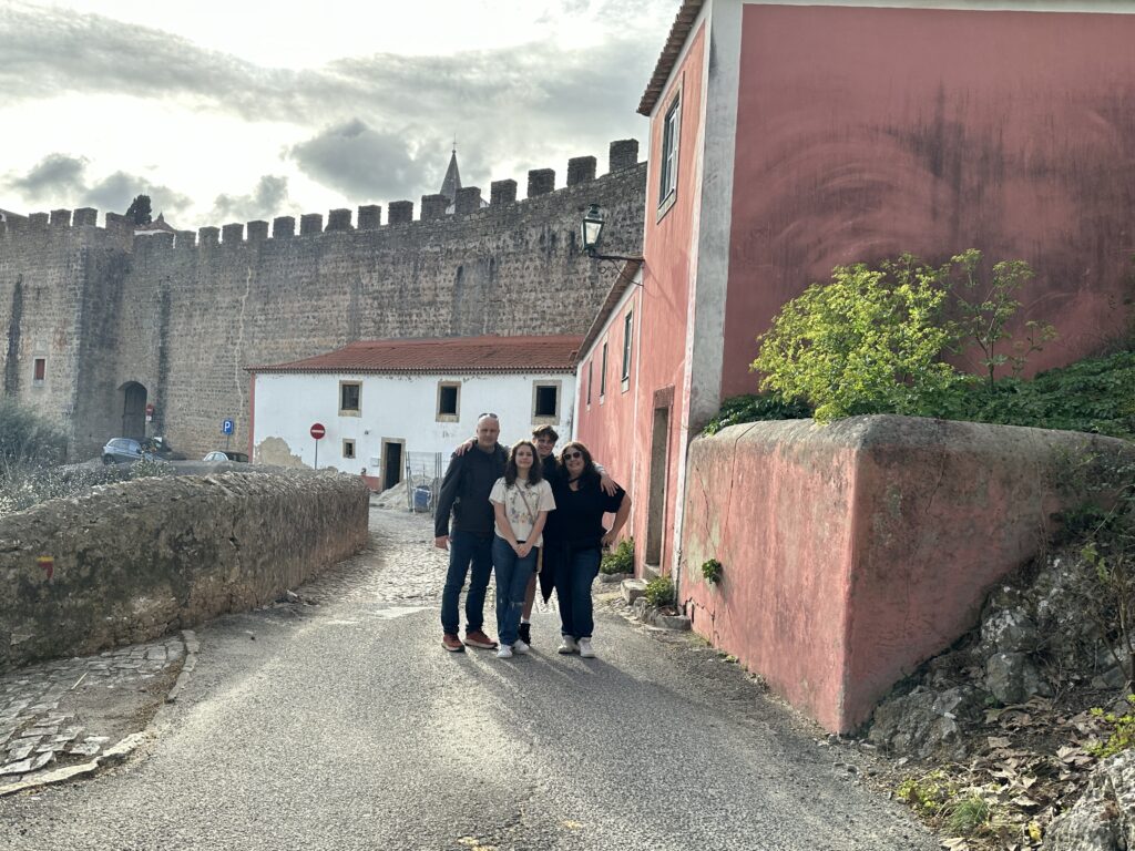 a group of people standing on a road in front of a stone wall