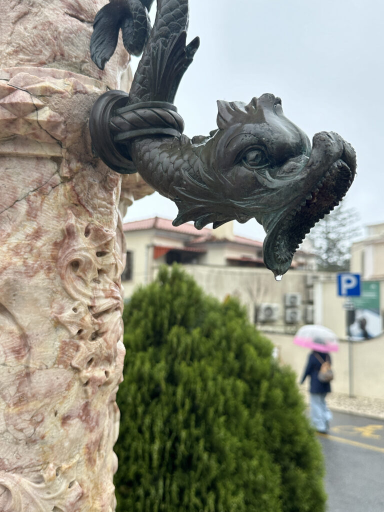 a statue of a fish head with water dripping from a fountain