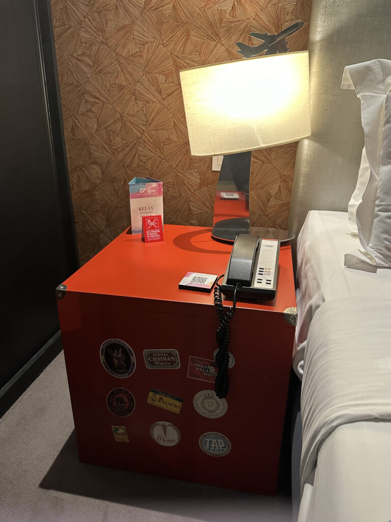 a red box with a telephone and a lamp on the side of the bed