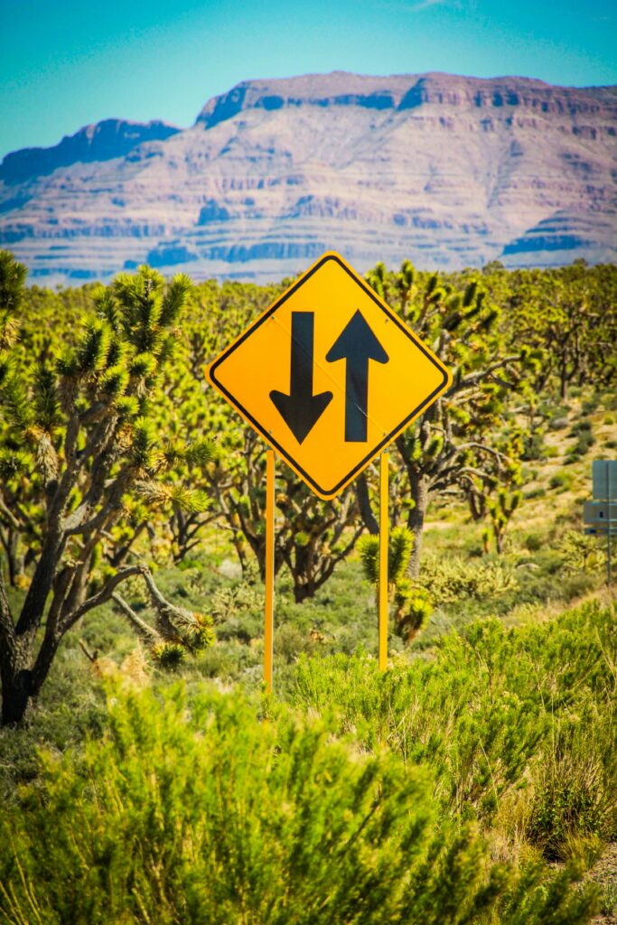 a yellow road sign with arrows pointing to the left