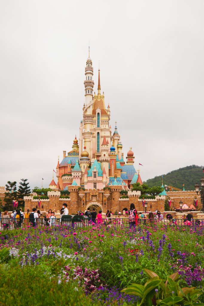 a castle with many towers and people in front of it with Disneyland Paris in the background