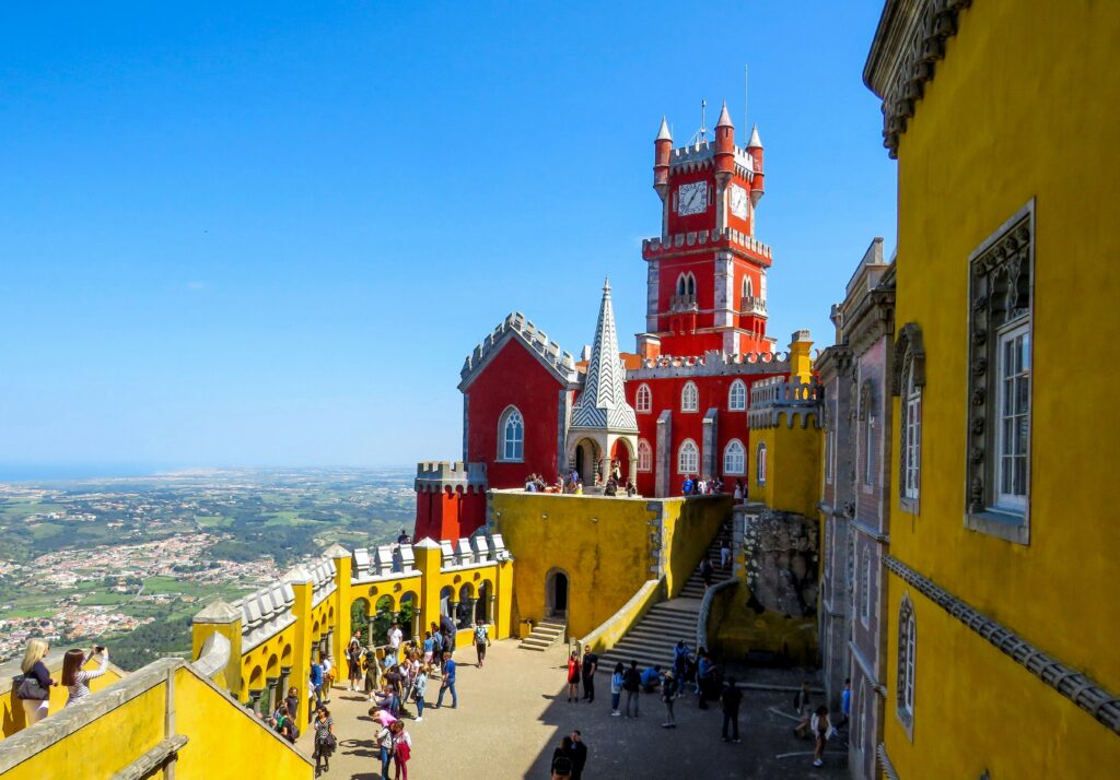 a group of people walking around a red and yellow building