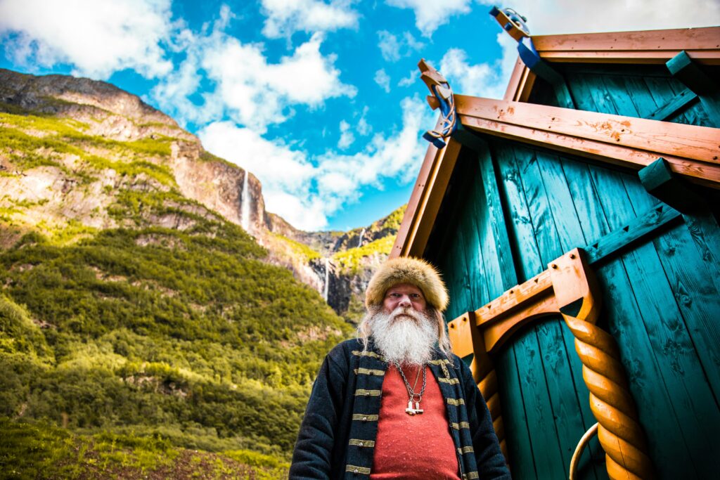 a man with a beard and fur hat standing in front of a blue house
