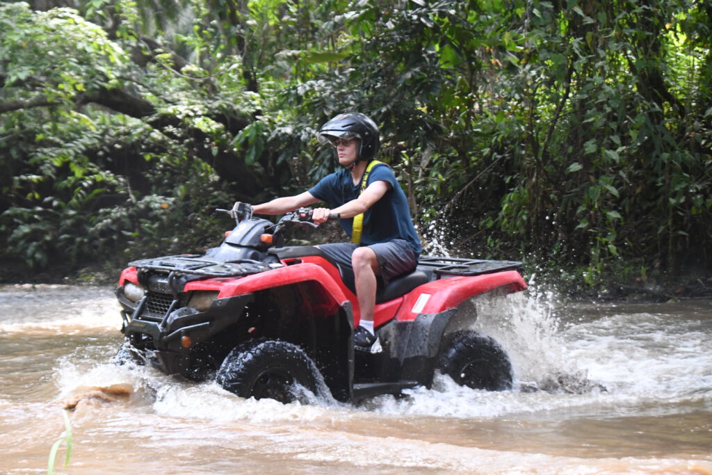 a man riding a four wheeler through water