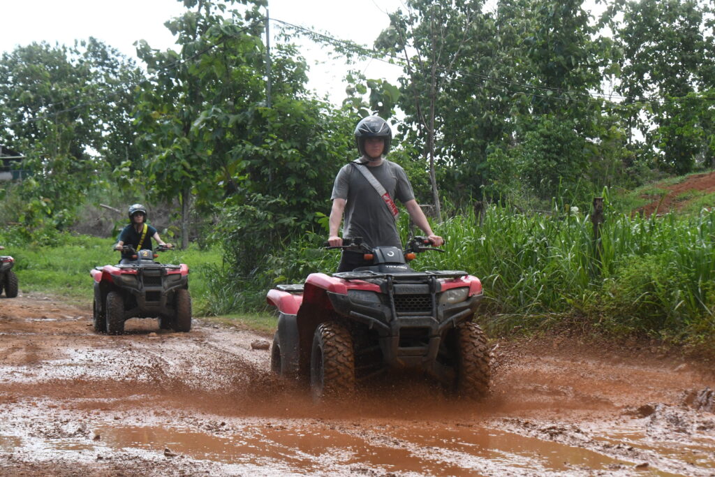 a group of people riding atvs on a muddy road