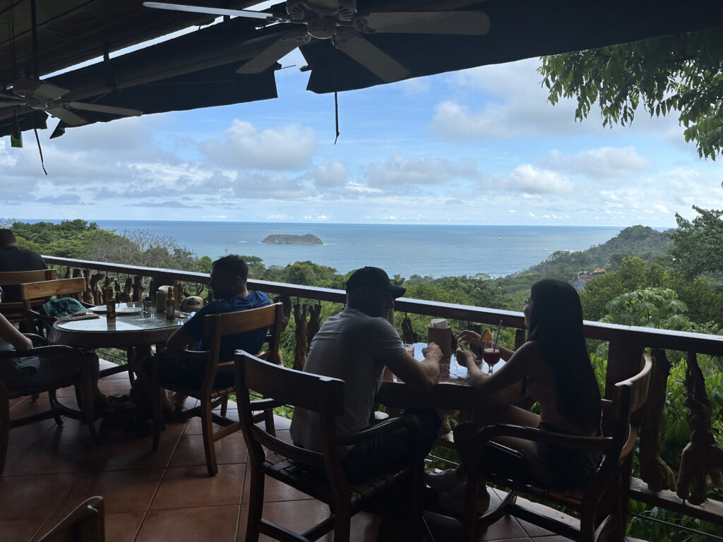 a group of people sitting at a table with a view of the ocean