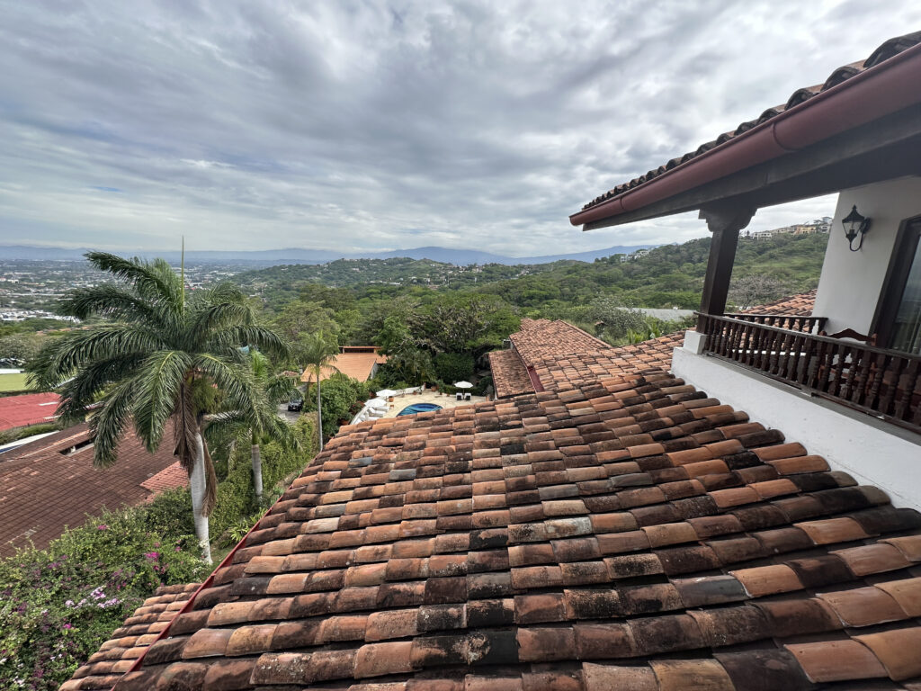 a roof of a house with trees and a cloudy sky