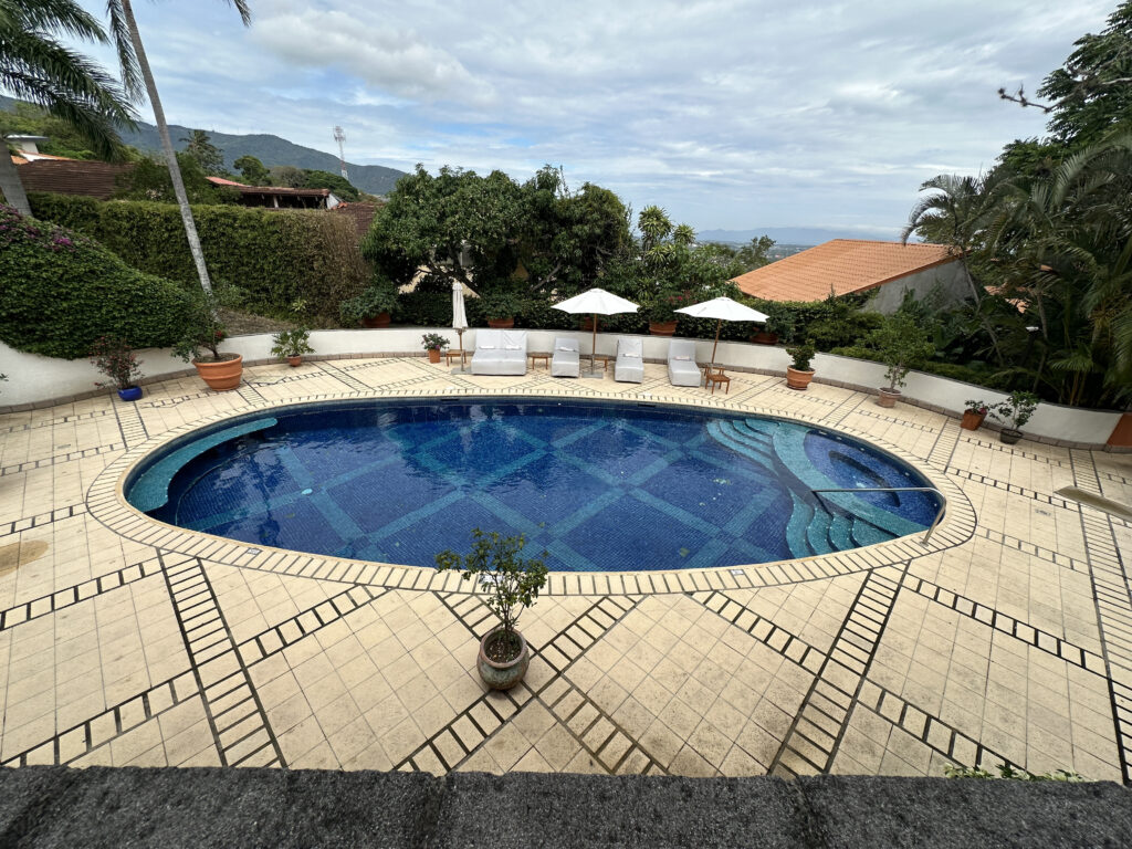 a swimming pool with chairs and trees