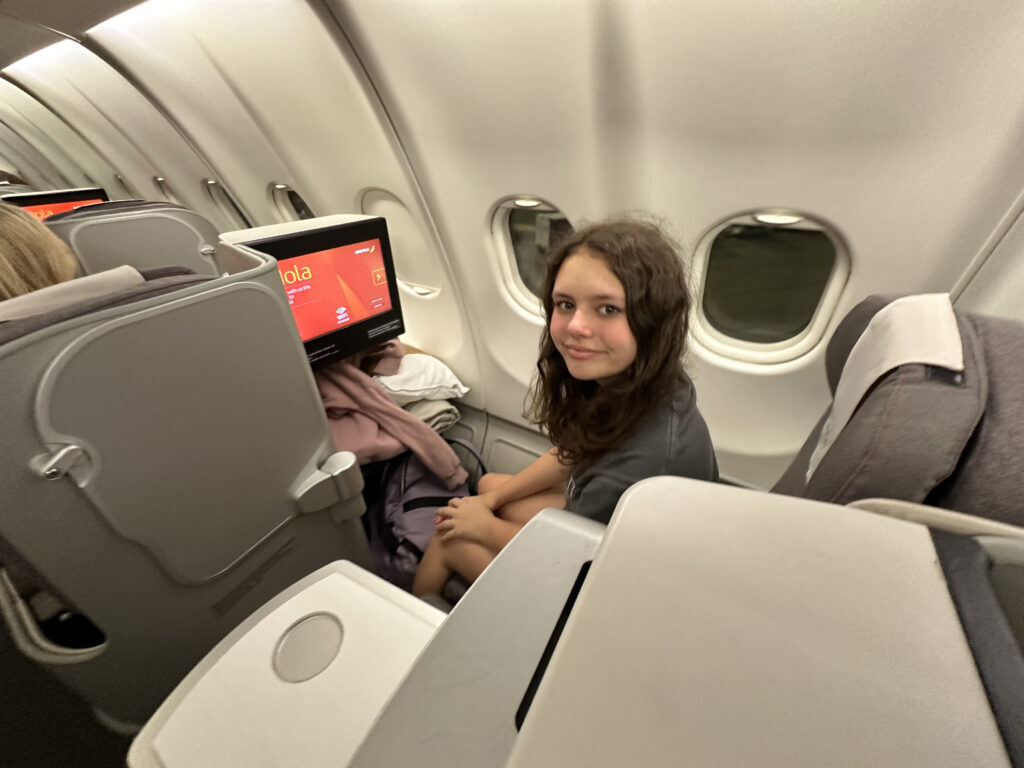 a girl sitting in an airplane with a television