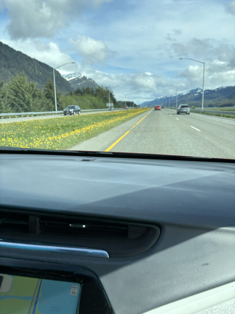 a view from a car window of a road with a mountain and trees