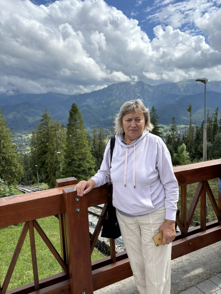 a woman standing on a railing with mountains in the background