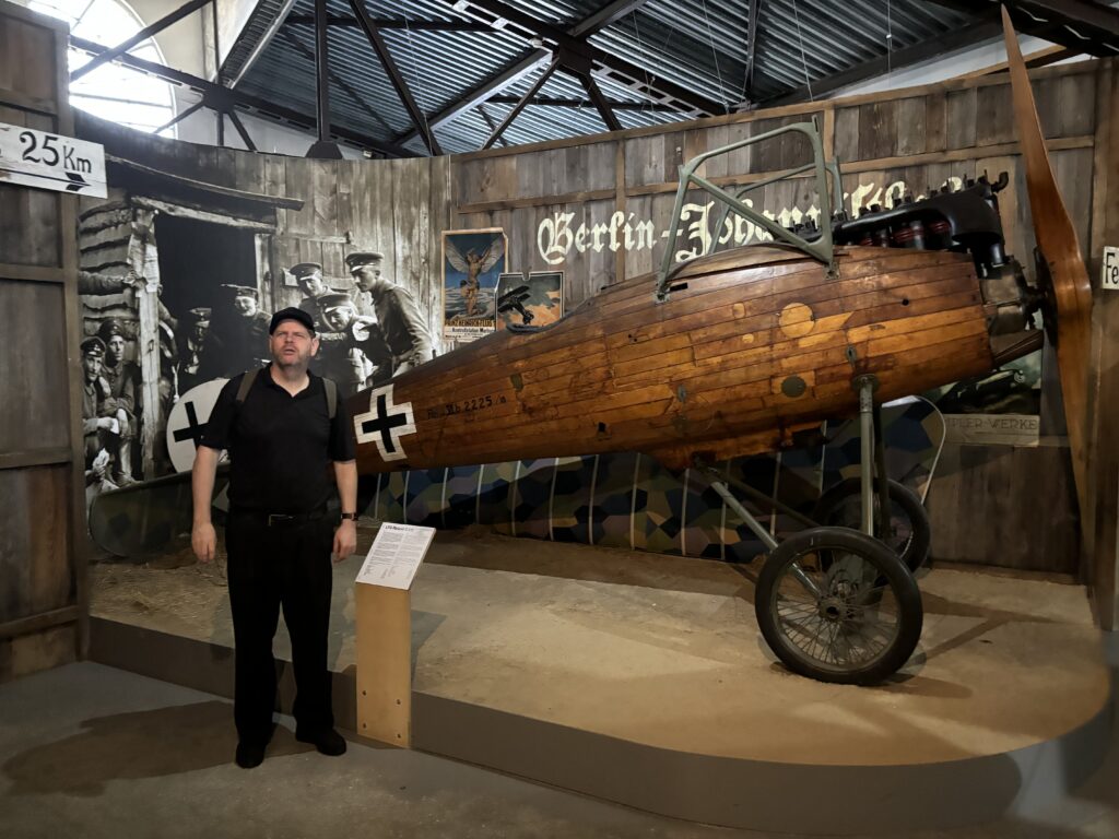 a man standing in front of a wooden airplane