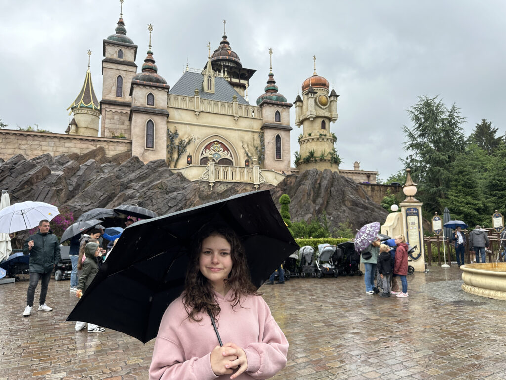 a girl holding an umbrella in front of a castle